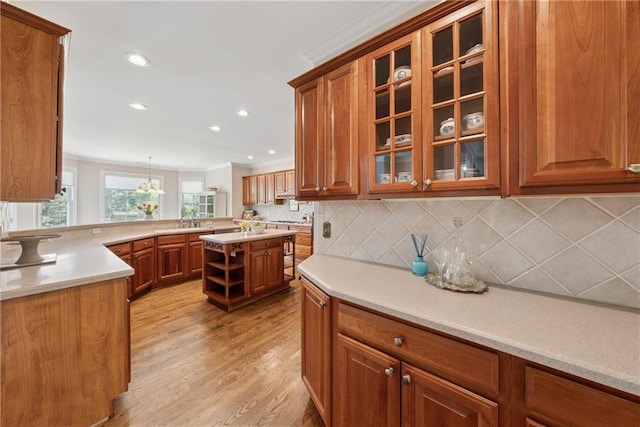 4790 Hyde Rd, Cumming, GA 30040 - kitchen featuring light wood finished floors, backsplash, glass insert cabinets, brown cabinets, and light countertops