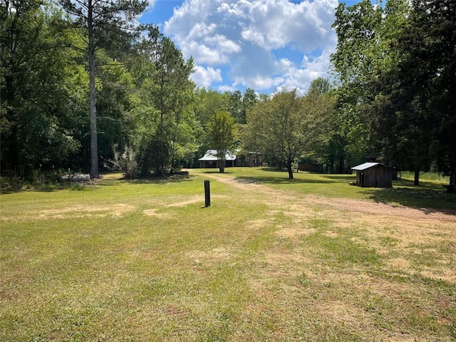 view of home's community featuring an outdoor structure, a shed, a yard, and a view of trees