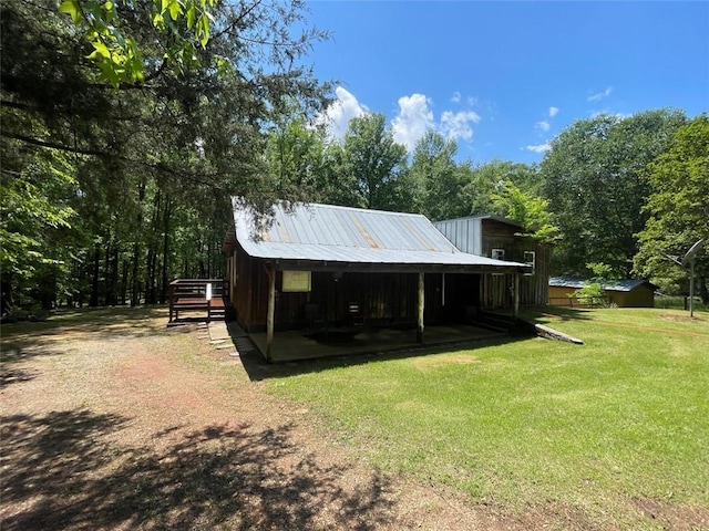 rear view of house featuring an outdoor structure, a shed, metal roof, and a yard
