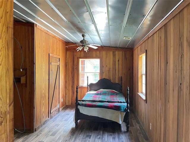 bedroom featuring wood finished floors, wooden walls, and visible vents