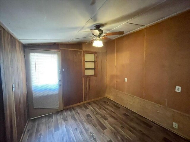 interior space featuring wood walls, wood finished floors, and a ceiling fan
