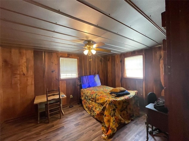 bedroom with wooden walls, wood finished floors, and ceiling fan