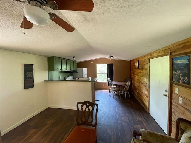 dining area featuring dark wood-style floors, a textured ceiling, wood walls, and lofted ceiling