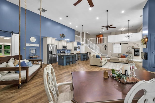 659 Creek Nation Rd, Jefferson, GA 30549 - dining space featuring a ceiling fan, a barn door, a towering ceiling, wood finished floors, and recessed lighting