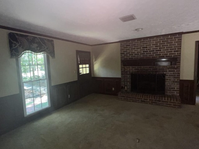unfurnished living room with crown molding, wood walls, carpet, and a brick fireplace