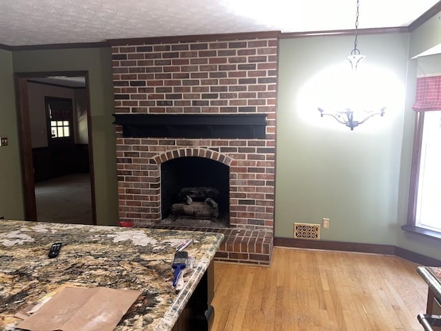 living room with ornamental molding, light hardwood / wood-style flooring, a textured ceiling, and a fireplace