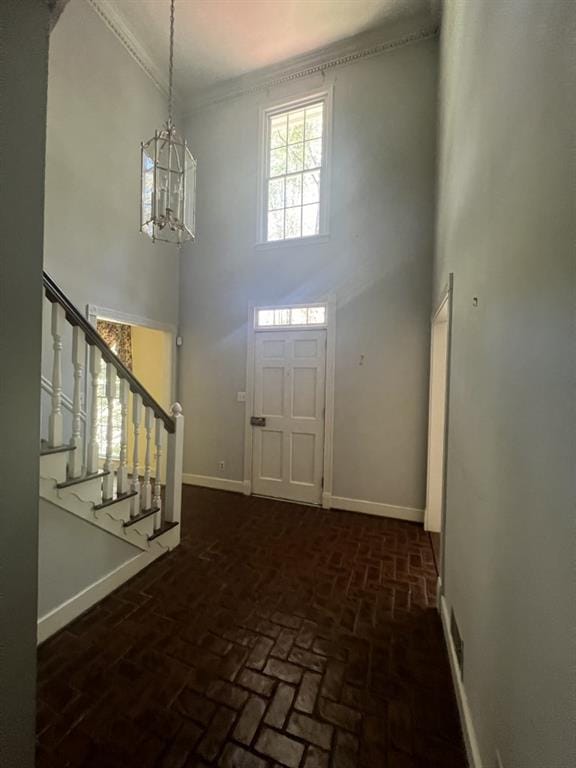 foyer entrance featuring a towering ceiling, crown molding, and a chandelier