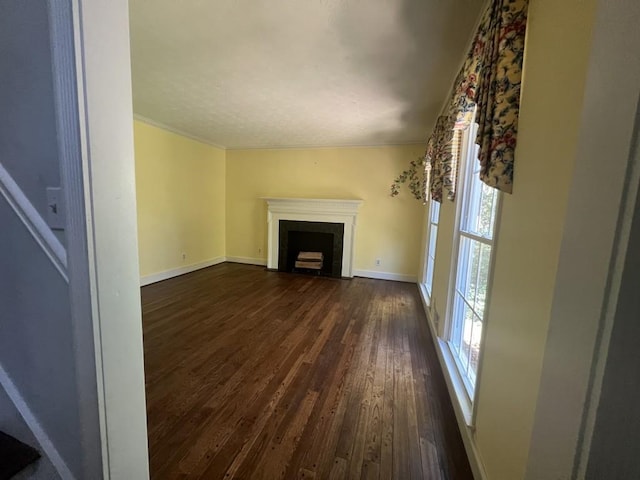 unfurnished living room featuring ornamental molding and dark wood-type flooring