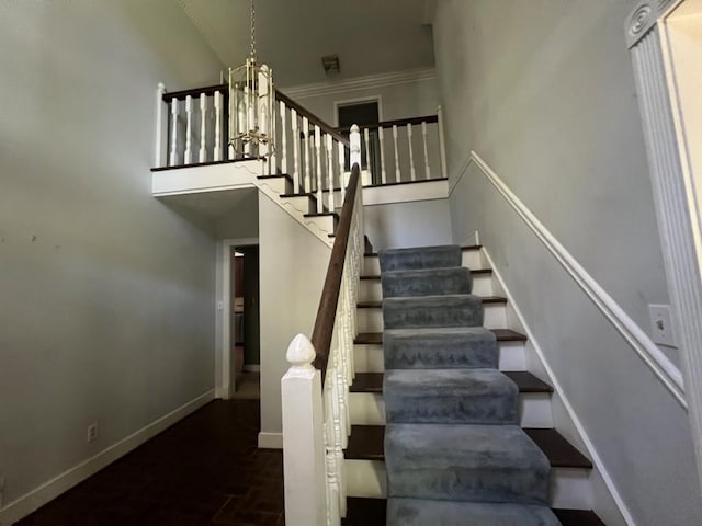 staircase with a notable chandelier, ornamental molding, and a high ceiling