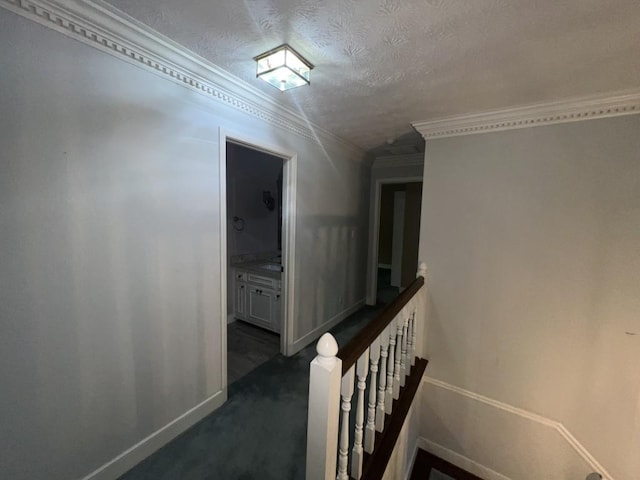 corridor featuring dark carpet, crown molding, and a textured ceiling