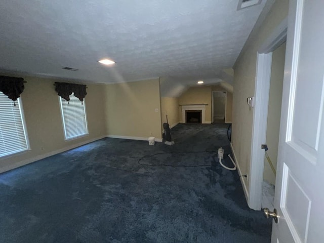 carpeted spare room featuring lofted ceiling and a textured ceiling