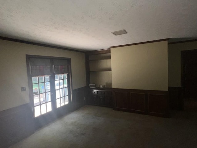 carpeted empty room featuring ornamental molding and a textured ceiling
