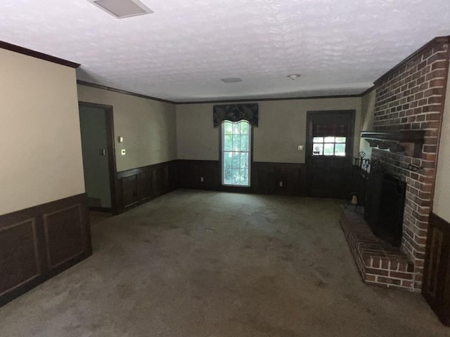 unfurnished living room with ornamental molding, a brick fireplace, a textured ceiling, and carpet floors