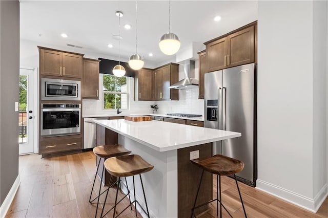 2535 Astaire Ct, Atlanta, GA 30318 - kitchen with appliances with stainless steel finishes, wall chimney range hood, tasteful backsplash, a kitchen breakfast bar, and light wood finished floors