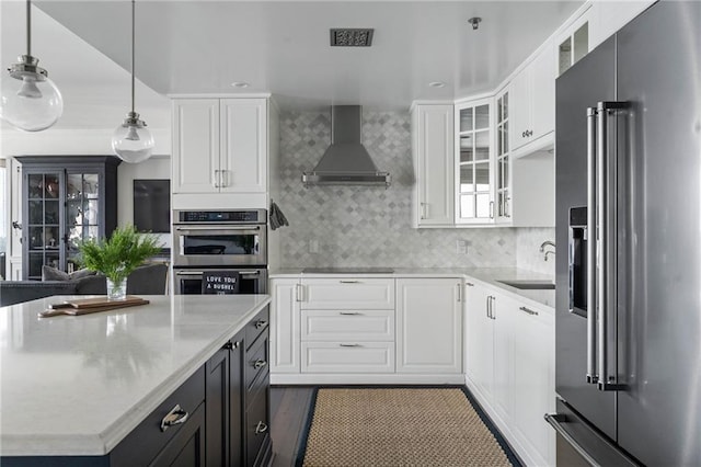 kitchen featuring pendant lighting, white cabinets, wall chimney exhaust hood, and appliances with stainless steel finishes