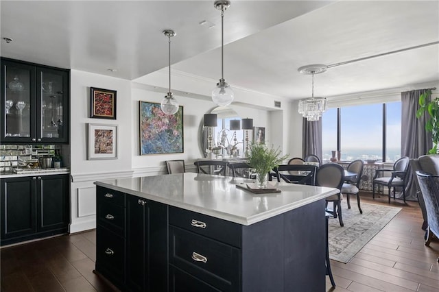 kitchen with pendant lighting, a kitchen bar, a center island, and dark wood-type flooring