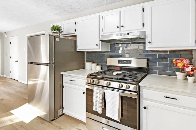 kitchen with white cabinetry, stainless steel appliances, tasteful backsplash, a textured ceiling, and light wood-type flooring