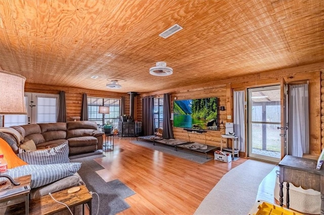 living room with wooden ceiling, light hardwood / wood-style floors, rustic walls, and a wood stove