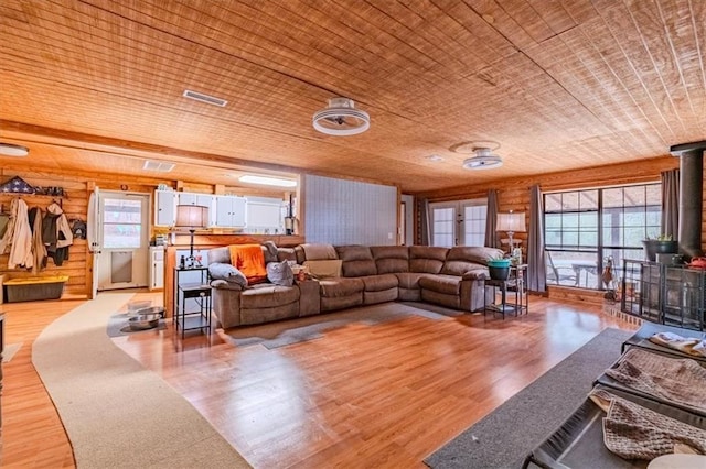 living room featuring hardwood / wood-style flooring, a wood stove, wood ceiling, and wood walls