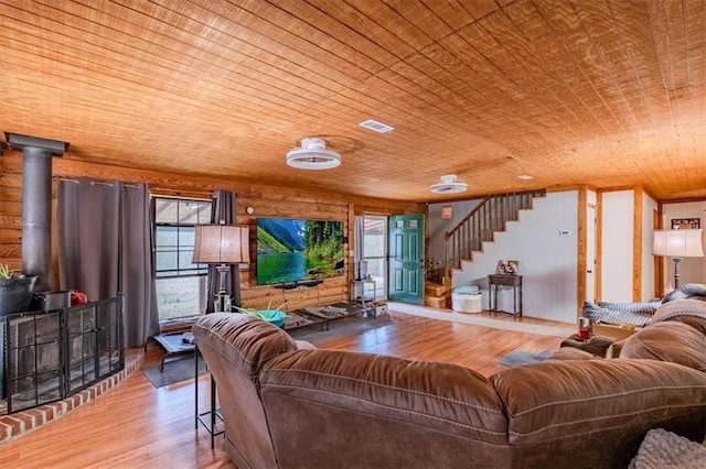 living room with a wood stove, wood ceiling, and light hardwood / wood-style flooring