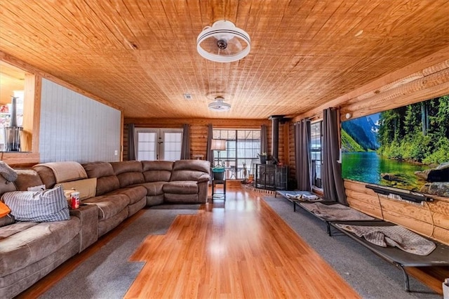 living room featuring hardwood / wood-style floors, wood ceiling, rustic walls, and a wood stove