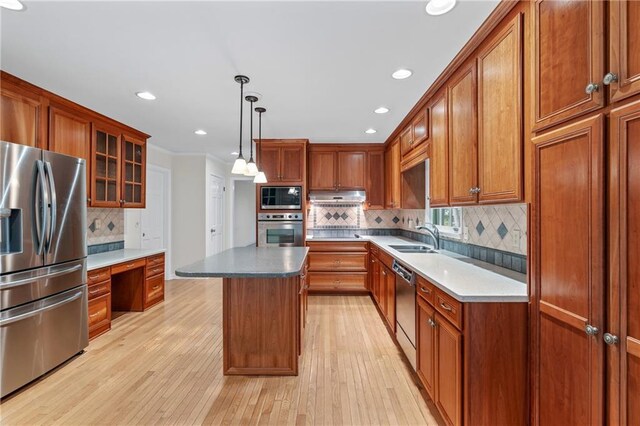 870 Richmond Hill Dr, Marietta, GA 30068 - kitchen featuring appliances with stainless steel finishes, brown cabinets, a sink, under cabinet range hood, and tasteful backsplash