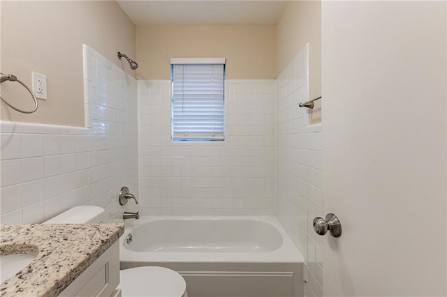 full bathroom featuring vanity, tiled shower / bath, tile walls, and toilet