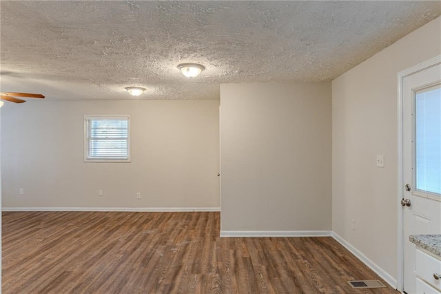 unfurnished room with dark hardwood / wood-style flooring, a textured ceiling, and ceiling fan