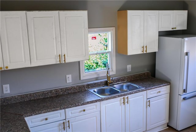 kitchen with white cabinets, white refrigerator, and sink