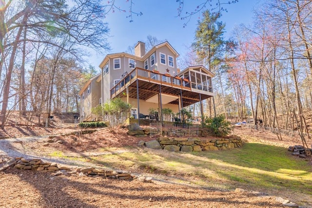 back of property with a wooden deck, a sunroom, a chimney, a yard, and a patio area