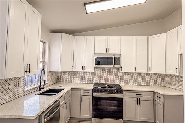 kitchen with lofted ceiling, a sink, gas range oven, dishwasher, and stainless steel microwave