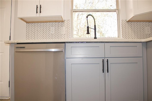 kitchen featuring dishwasher, decorative backsplash, and white cabinetry