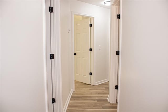 hallway featuring baseboards and light wood-style flooring