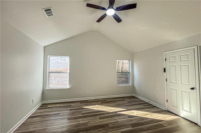 spare room featuring visible vents, dark wood finished floors, baseboards, ceiling fan, and vaulted ceiling