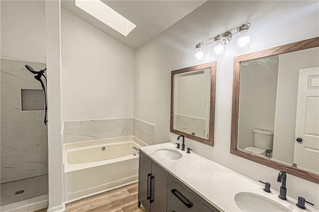 full bathroom with a garden tub, wood finished floors, double vanity, and a sink