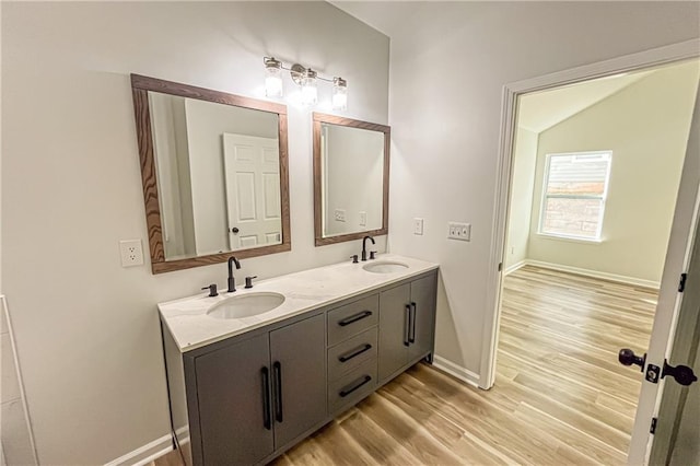 full bathroom featuring double vanity, wood finished floors, baseboards, and a sink