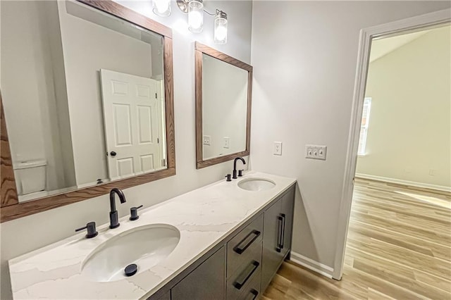 bathroom featuring double vanity, wood finished floors, baseboards, and a sink