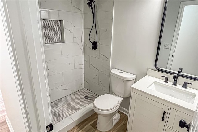 bathroom featuring vanity, wood finished floors, baseboards, a stall shower, and toilet