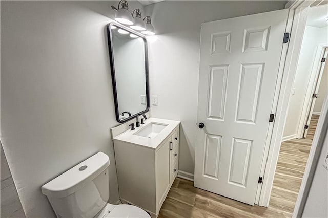 half bath featuring vanity, toilet, and wood finished floors