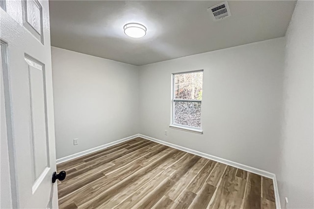 unfurnished room featuring visible vents, dark wood-type flooring, and baseboards