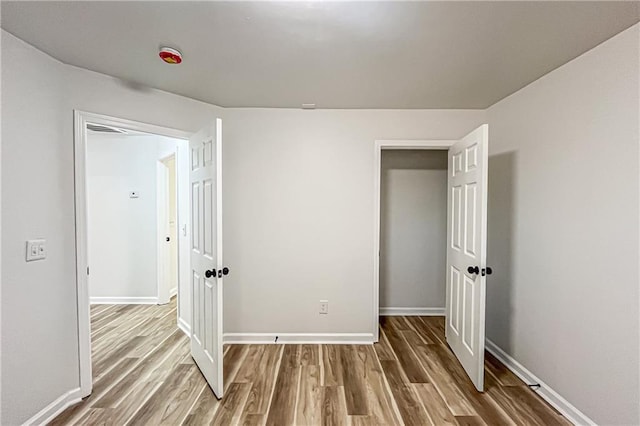 unfurnished bedroom featuring wood finished floors and baseboards