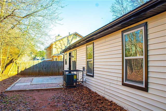 view of side of property with a patio area, central AC unit, and fence