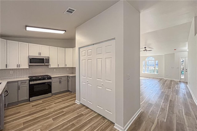 kitchen with visible vents, gray cabinetry, light countertops, decorative backsplash, and stainless steel appliances