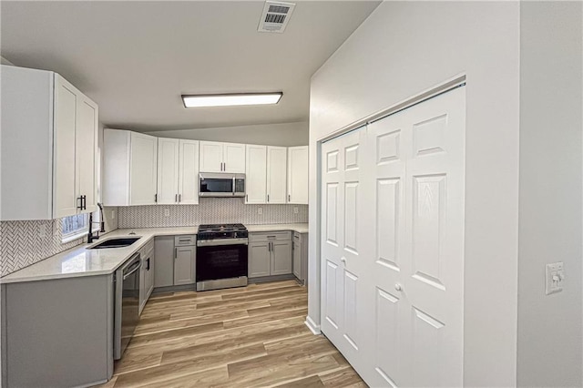 kitchen with a sink, decorative backsplash, appliances with stainless steel finishes, and gray cabinets