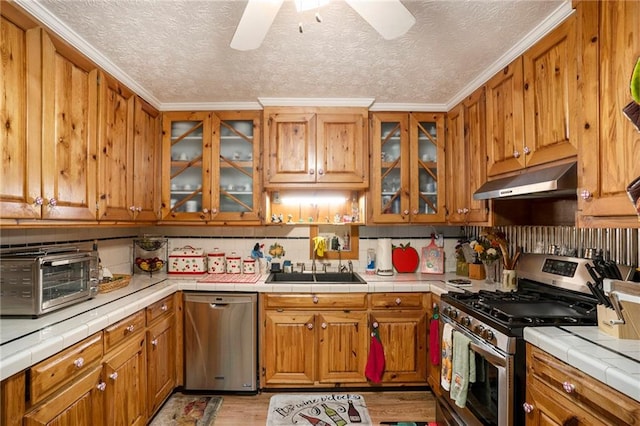 kitchen with light hardwood / wood-style flooring, tile countertops, sink, and stainless steel appliances