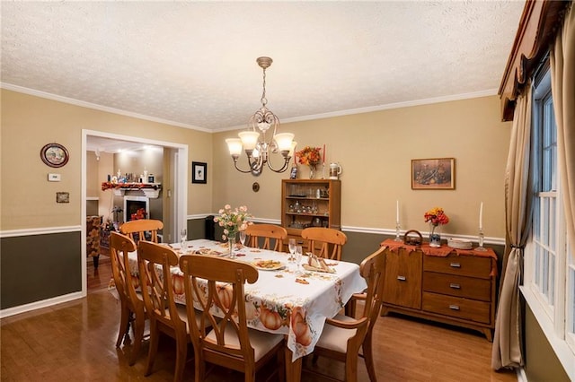 dining space with hardwood / wood-style floors, an inviting chandelier, a textured ceiling, and ornamental molding