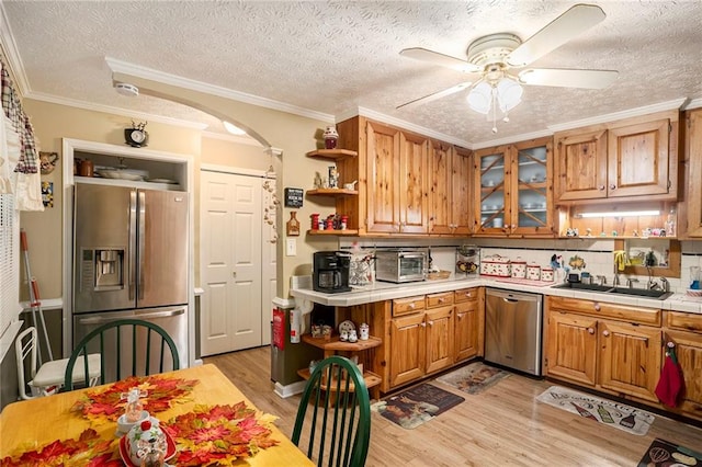 kitchen with ceiling fan, sink, stainless steel appliances, light hardwood / wood-style floors, and ornamental molding