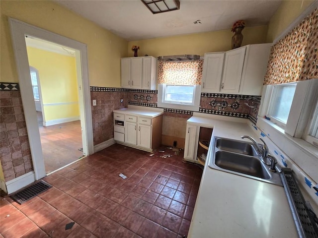 kitchen with white cabinetry, sink, tile walls, and dark tile patterned flooring