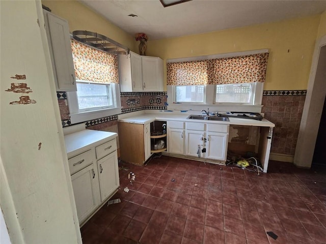 kitchen with white cabinetry, sink, and tile walls