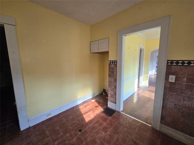 tiled spare room featuring tile walls